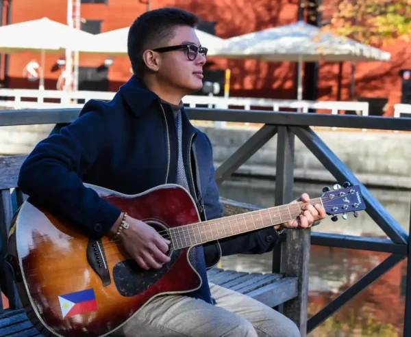 Spencer Strandh sittandes utomhus med en gitarr
