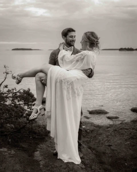 Svartvit bild på ett brudbar där mannen bär kvinnan